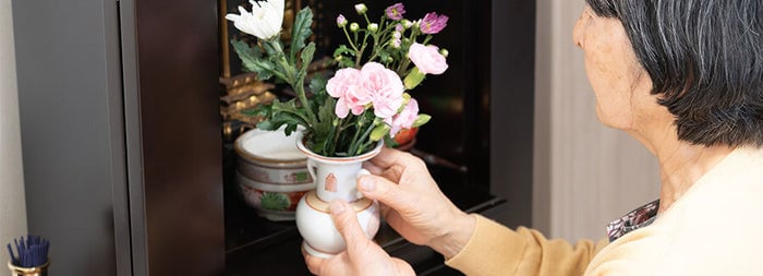 お仏壇に花を供える年配の女性