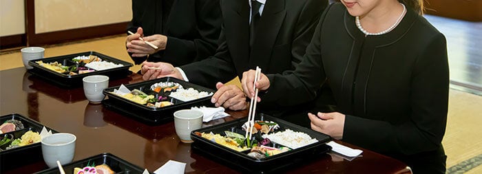 喪服を着用して会食する人たち