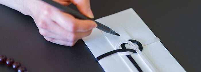 筆ペンで不祝儀袋に表書きをする手元