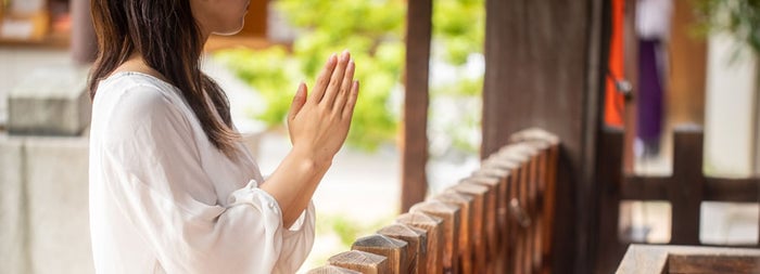 神社で手を合わせる女性