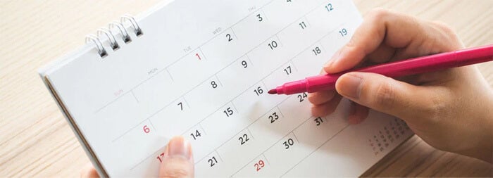 カレンダーで日程確認をしているイメージ画像