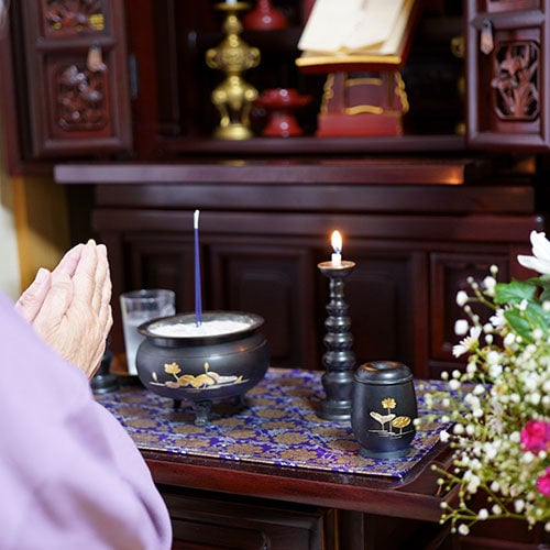 仏壇に手を合わせる女性の画像